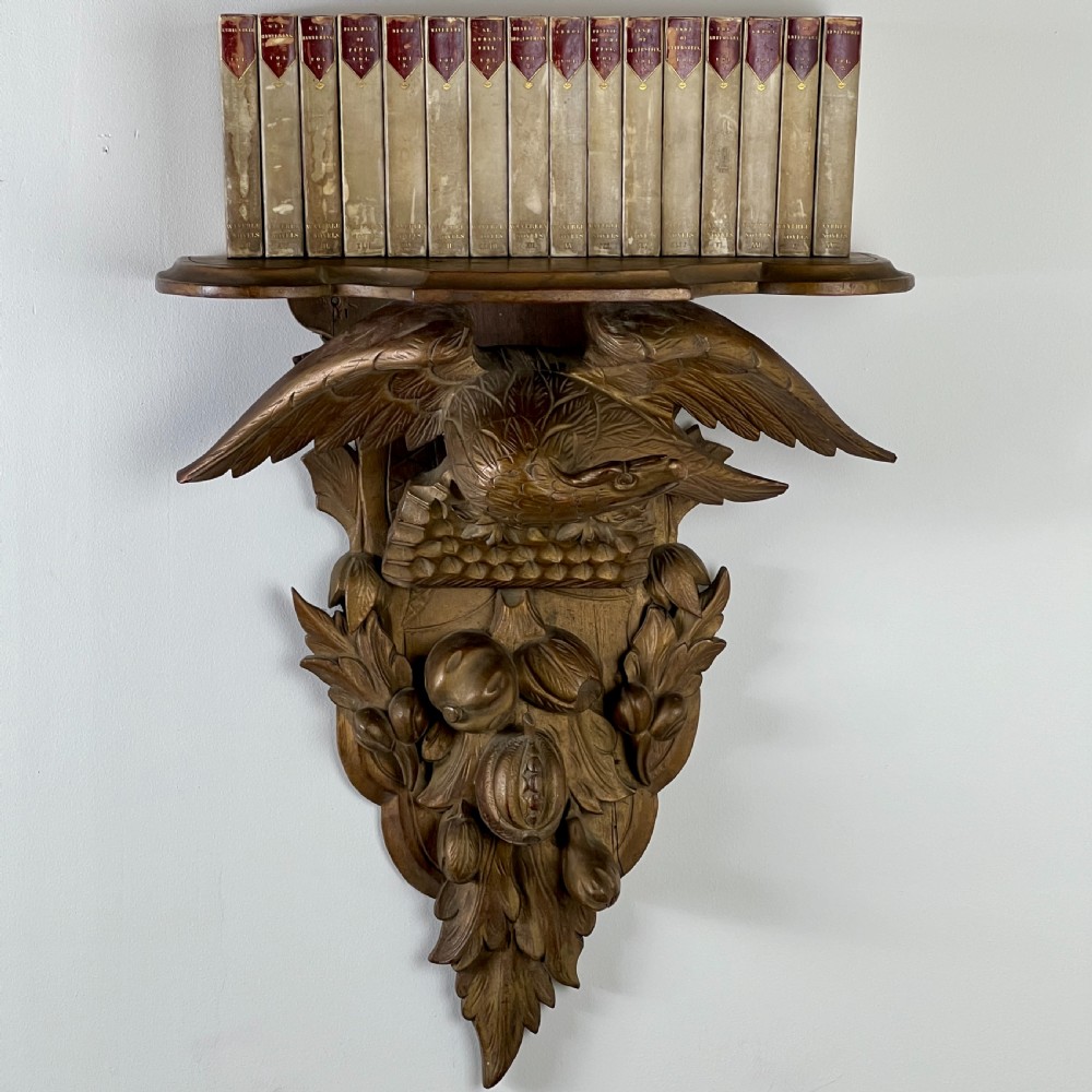 A 19th-century carved giltwood wall bracket featuring a spread-winged eagle above carved fruit and acanthus leaf details. View VI