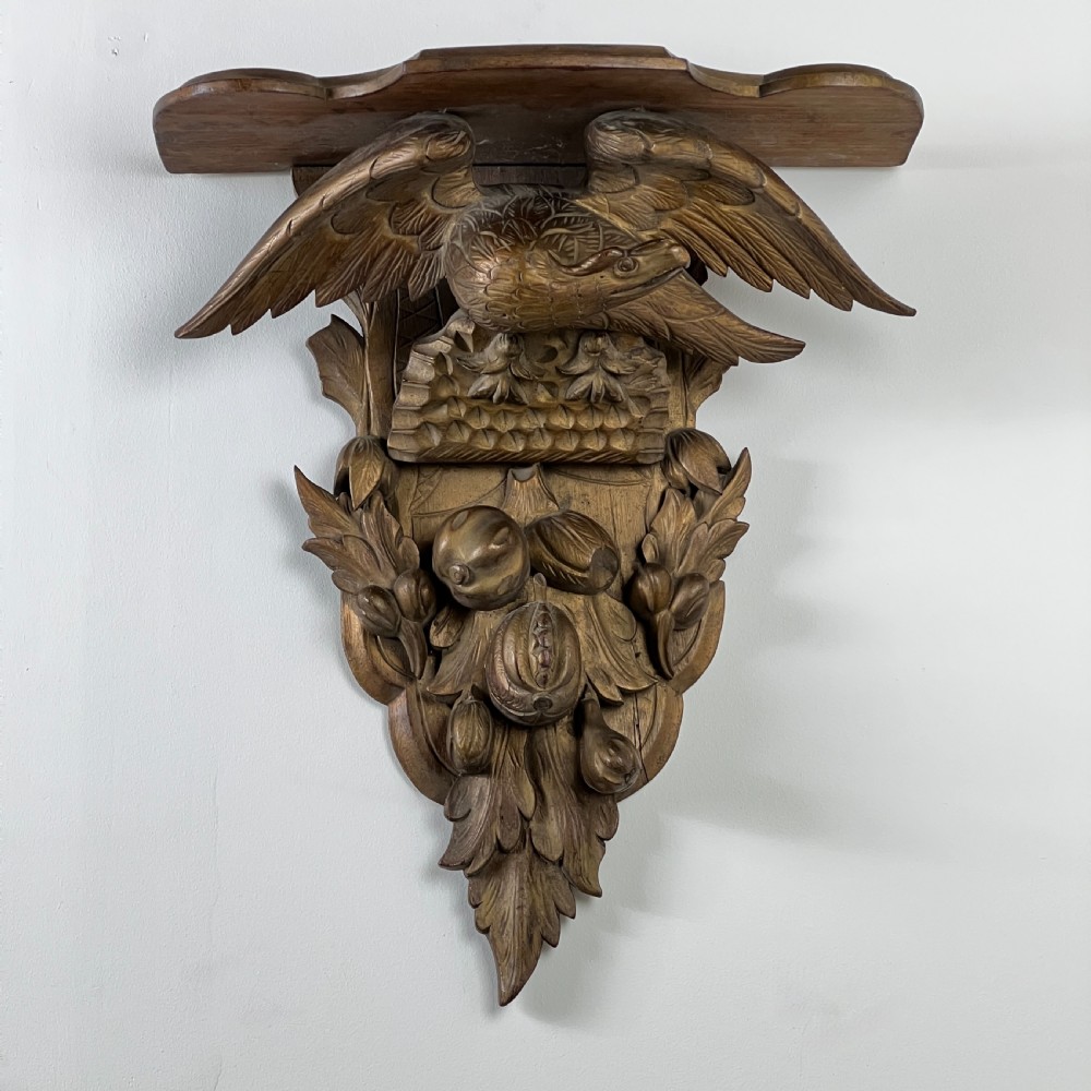 A 19th-century carved giltwood wall bracket featuring a spread-winged eagle above carved fruit and acanthus leaf details. View IX