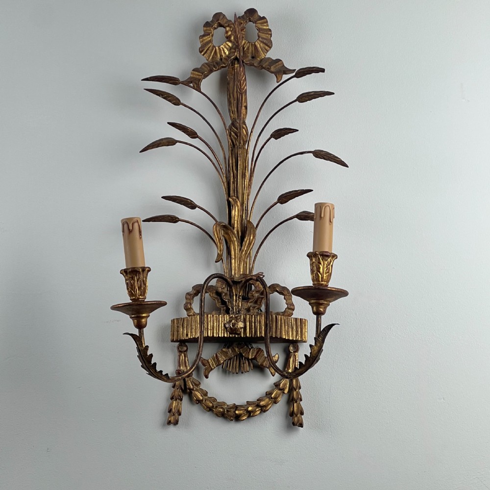A pair of early 20th-century Italian giltwood and toleware wall sconces featuring carved ribbon bow crests, rising foliage sprigs, and twin candle arms. View IV
