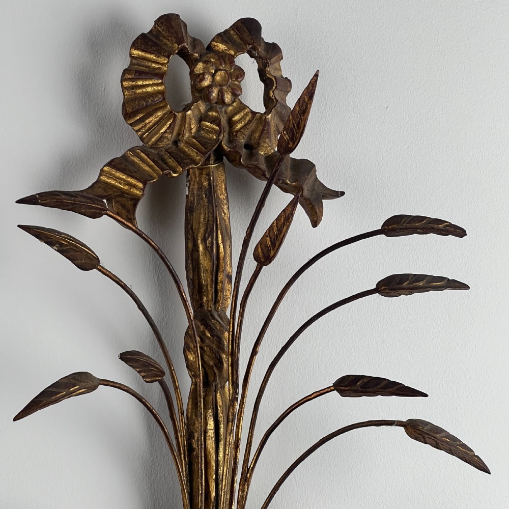 A pair of early 20th-century Italian giltwood and toleware wall sconces featuring carved ribbon bow crests, rising foliage sprigs, and twin candle arms. View VII