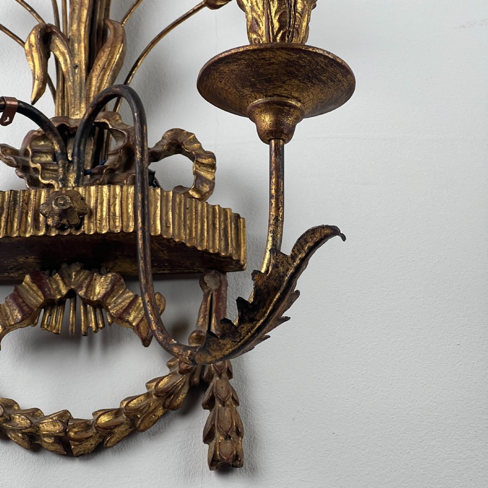 A pair of early 20th-century Italian giltwood and toleware wall sconces featuring carved ribbon bow crests, rising foliage sprigs, and twin candle arms. View VIII
