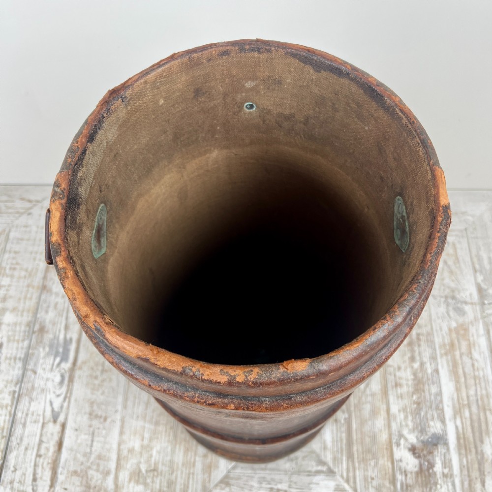 A tall cylindrical brown leather First World War artillery shell carrier featuring heavy stitched seams and a riveted side handle. View II
