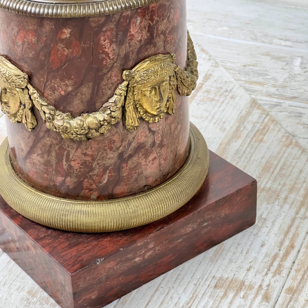 A pair of French Empire patinated bronze candelabra depicting winged victory figures standing on spheres atop rouge marble plinths with gilt bronze mounts. View VI