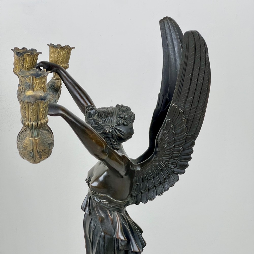 A pair of French Empire patinated bronze candelabra depicting winged victory figures standing on spheres atop rouge marble plinths with gilt bronze mounts. View XII