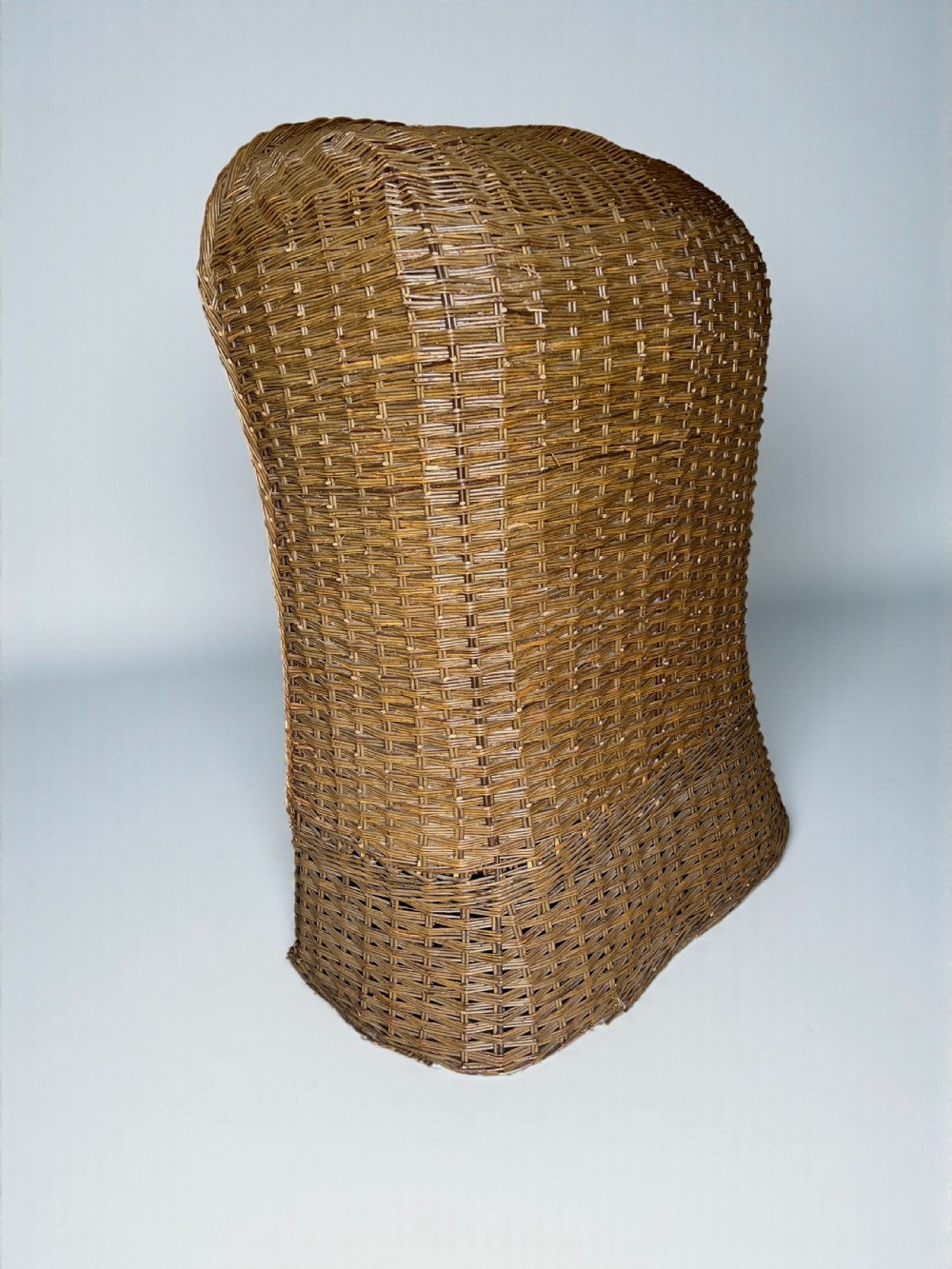 A high-backed woven wicker porters chair featuring a hooded canopy and floral upholstered linen interior. View VI
