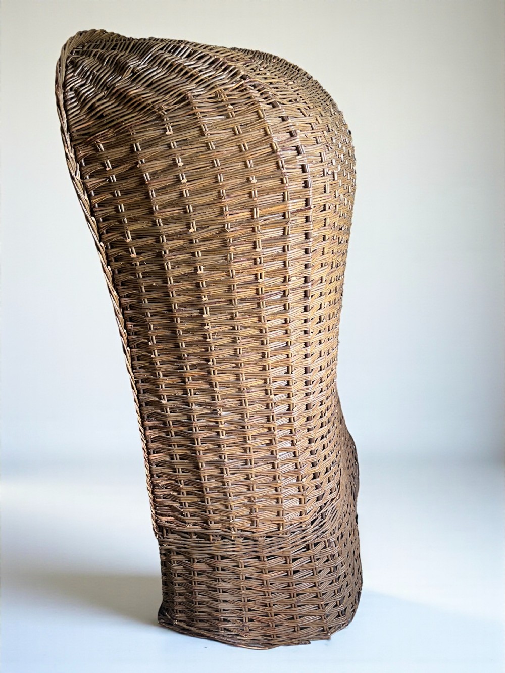A high-backed woven wicker porters chair featuring a hooded canopy and floral upholstered linen interior. View VII