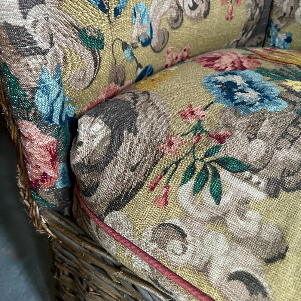 A high-backed woven wicker porters chair featuring a hooded canopy and floral upholstered linen interior. View IX