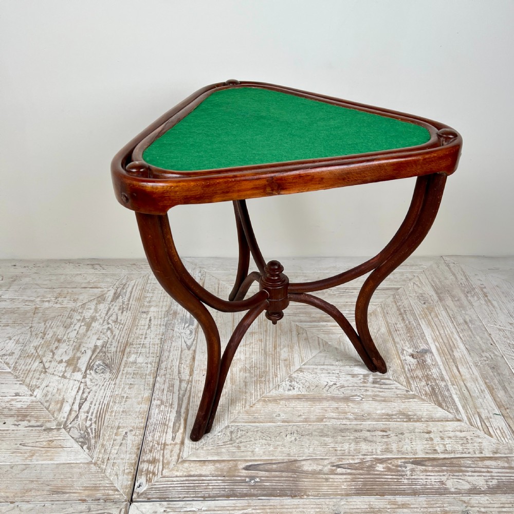 A triangular bentwood card table featuring a green felt playing surface, three curved legs, and a central turned wooden finial.