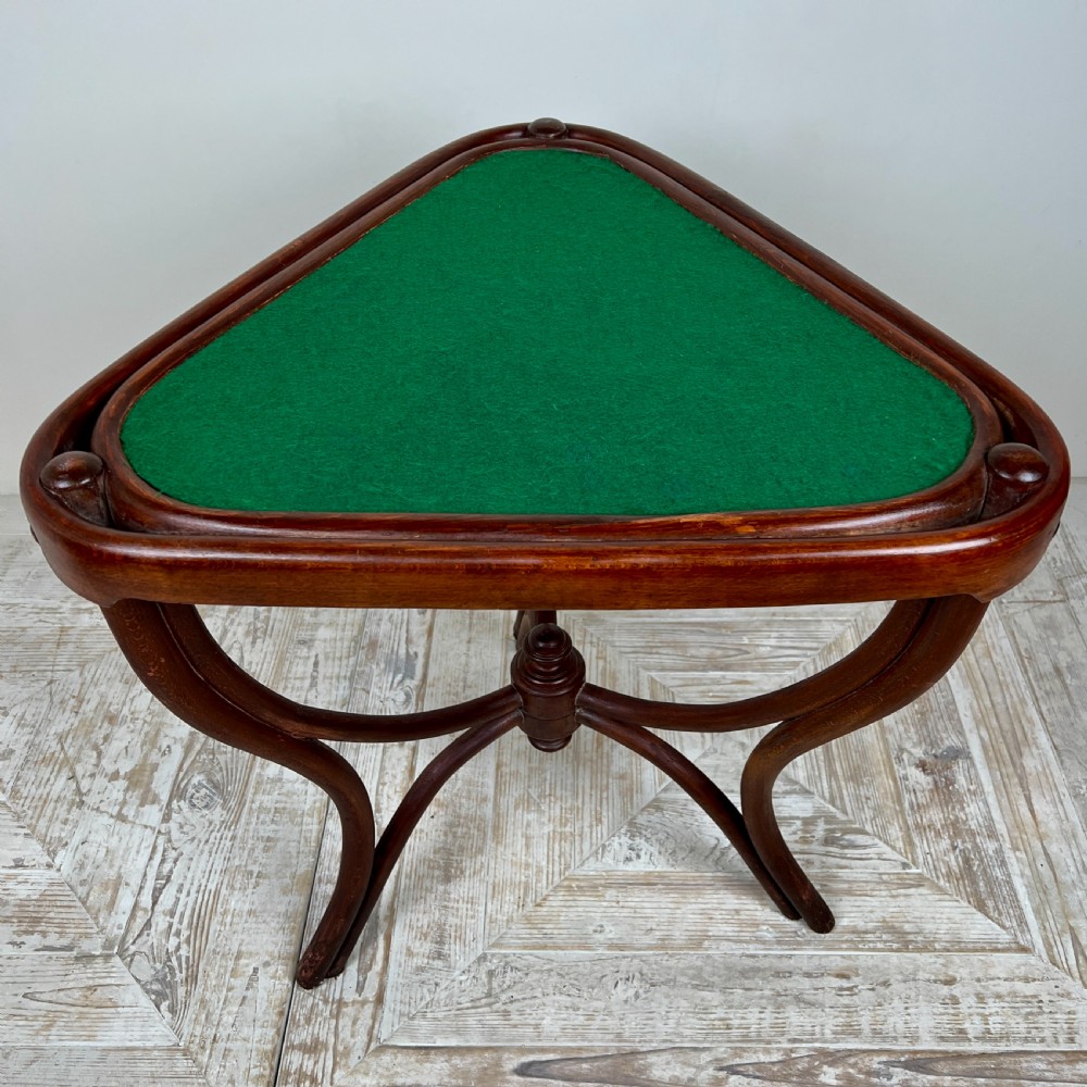 A triangular bentwood card table featuring a green felt playing surface, three curved legs, and a central turned wooden finial. View VII