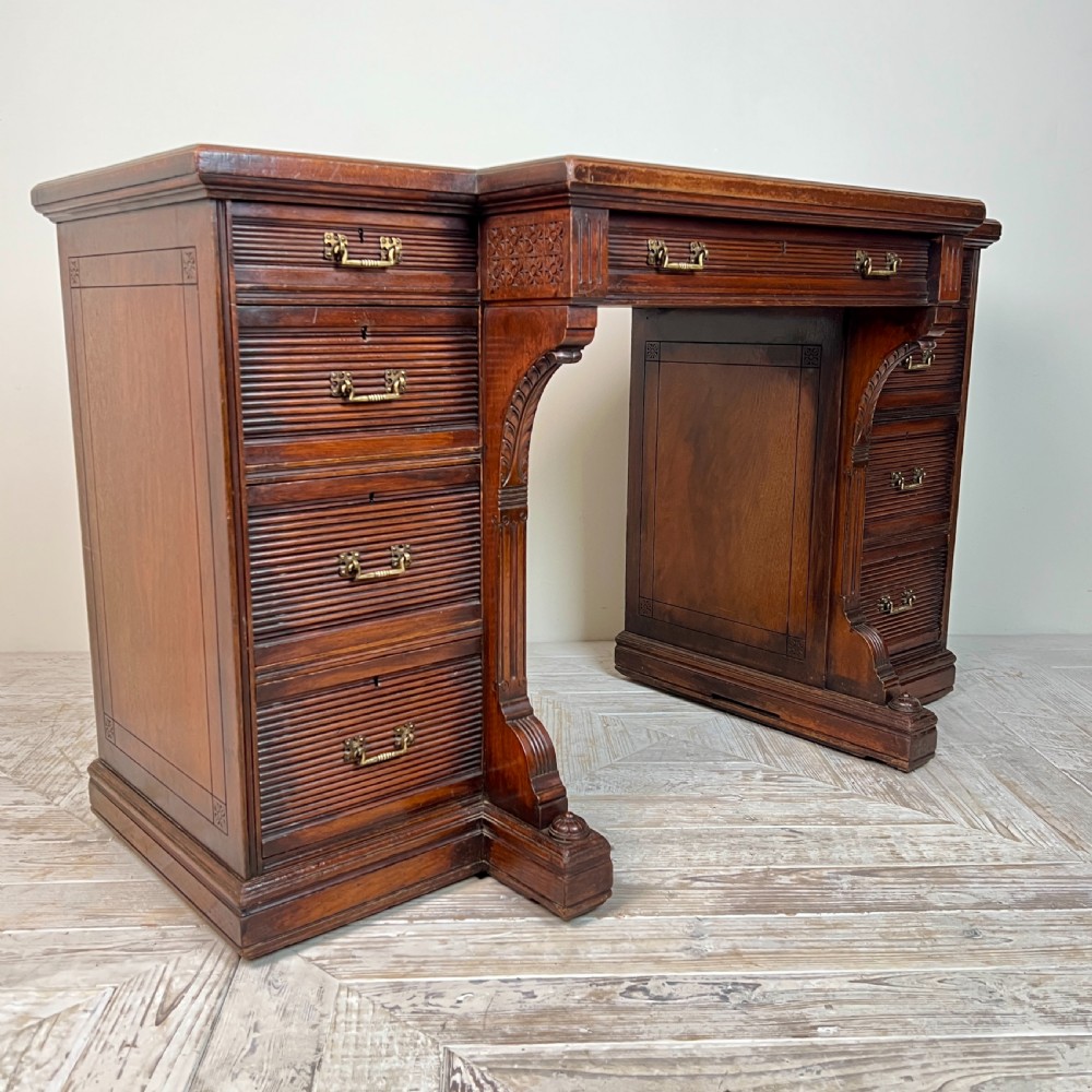 A Victorian mahogany breakfront pedestal desk featuring a green leather inset writing surface with gold tooling and multiple drawers with brass handles. View II