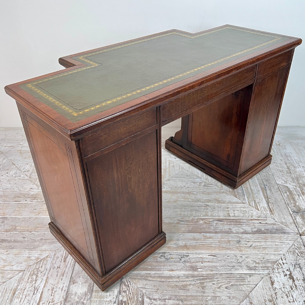 A Victorian mahogany breakfront pedestal desk featuring a green leather inset writing surface with gold tooling and multiple drawers with brass handles. View VII