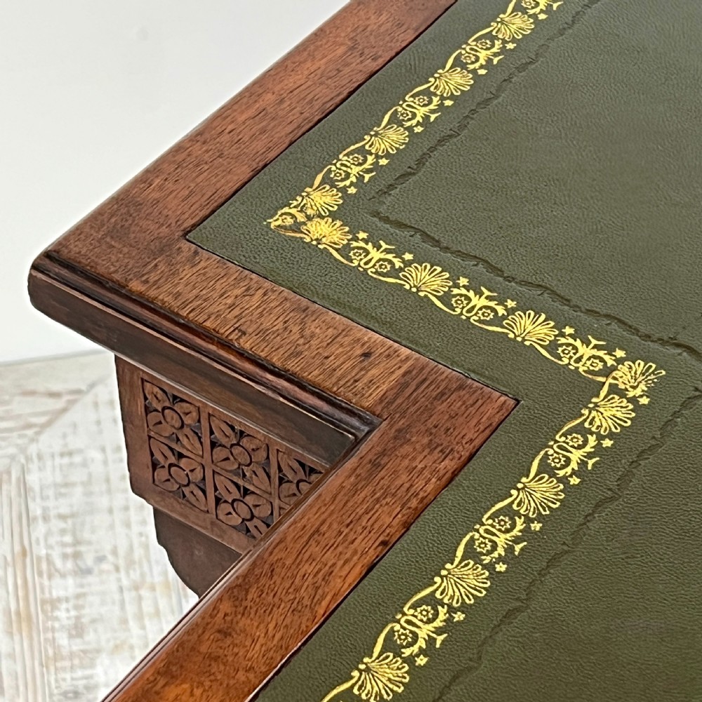 A Victorian mahogany breakfront pedestal desk featuring a green leather inset writing surface with gold tooling and multiple drawers with brass handles. View IX