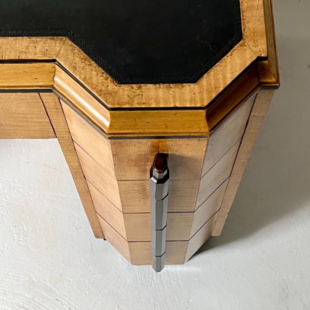 An Art Deco satin birch writing desk featuring a black leather top, stepped geometric corners, dark trim, and twin pedestals with drawers. View VIII