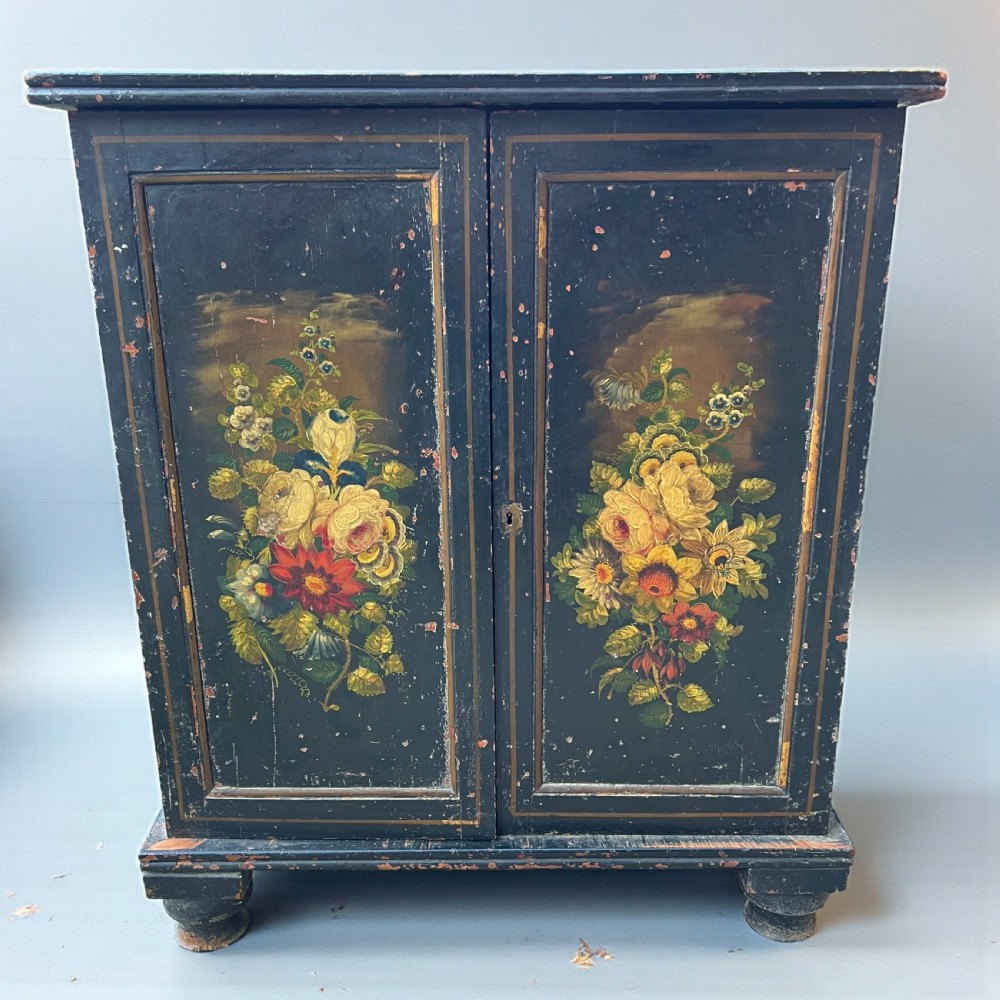 A Victorian ebonised black pine cabinet featuring two panelled doors decorated with hand-painted floral bouquets.