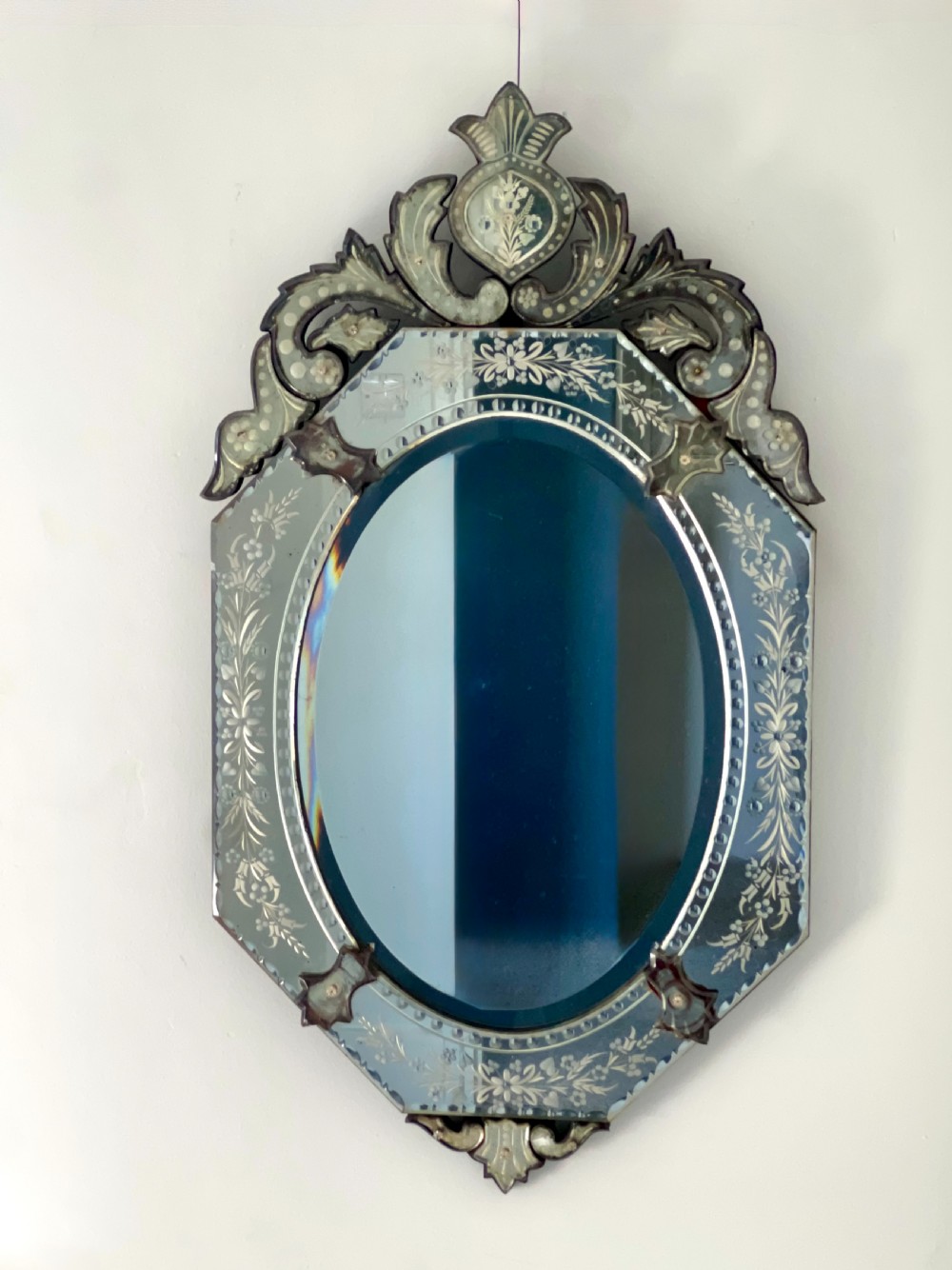 An octagonal Venetian-style wall mirror featuring etched floral borders, an oval central plate, and a decorative scrolling glass crest. View III