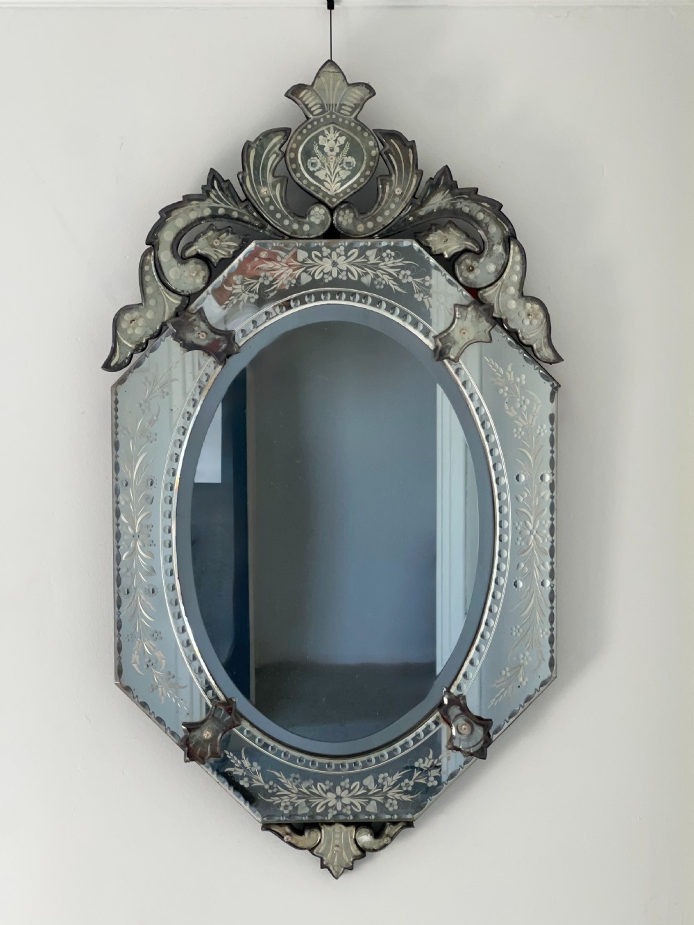 An octagonal Venetian-style wall mirror featuring etched floral borders, an oval central plate, and a decorative scrolling glass crest. View IV