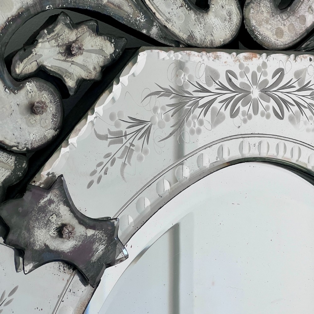 An octagonal Venetian-style wall mirror featuring etched floral borders, an oval central plate, and a decorative scrolling glass crest. View VI