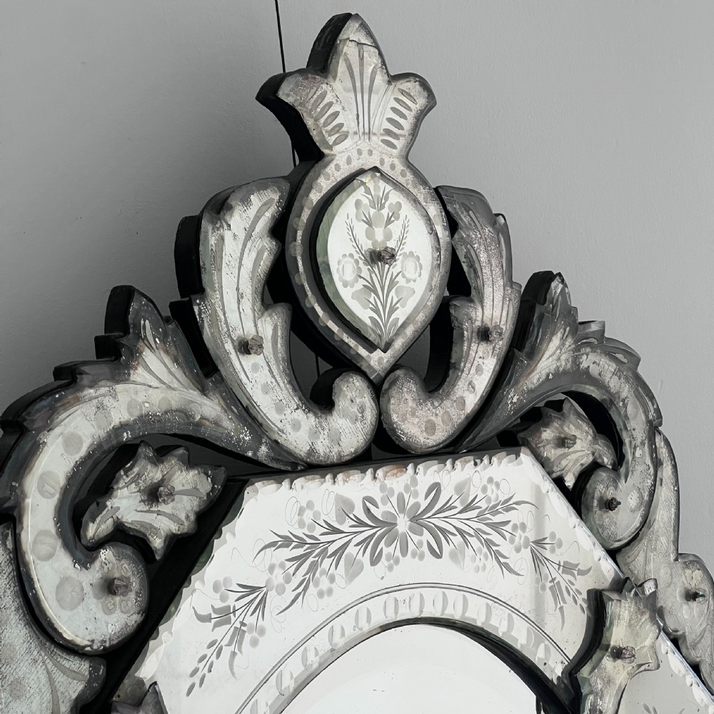An octagonal Venetian-style wall mirror featuring etched floral borders, an oval central plate, and a decorative scrolling glass crest. View VII