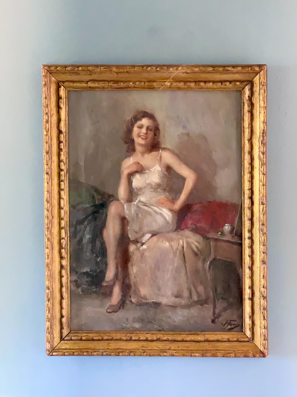 An oil painting depicting a seated woman in a light dress contained within an ornate gilt wooden frame. View II