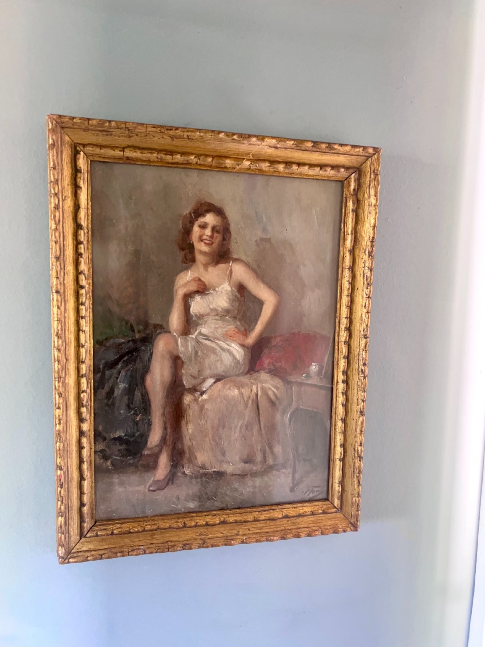 An oil painting depicting a seated woman in a light dress contained within an ornate gilt wooden frame. View V