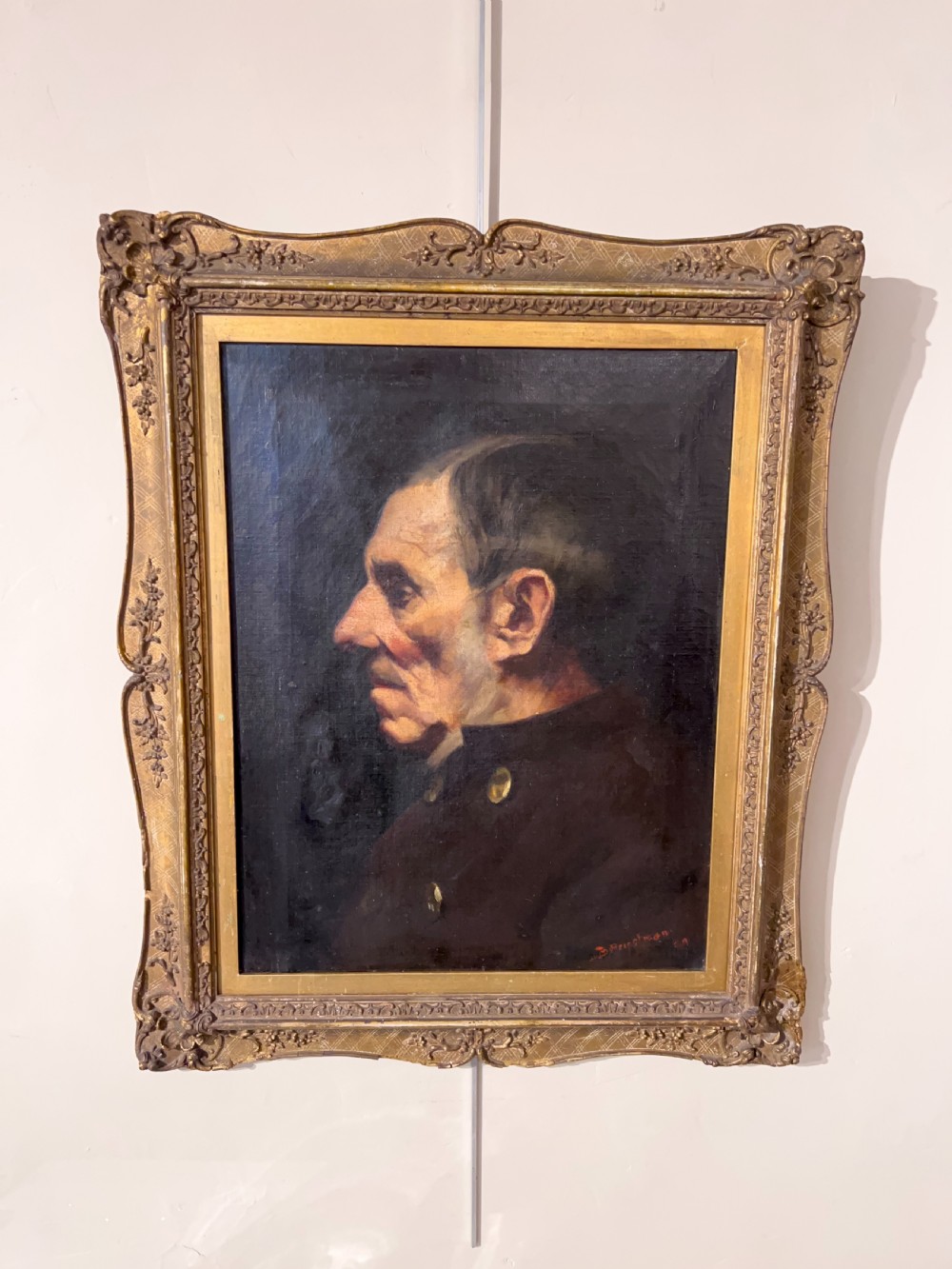 A side-profile oil portrait painting of a gentleman set within an ornate carved gilded wooden frame.