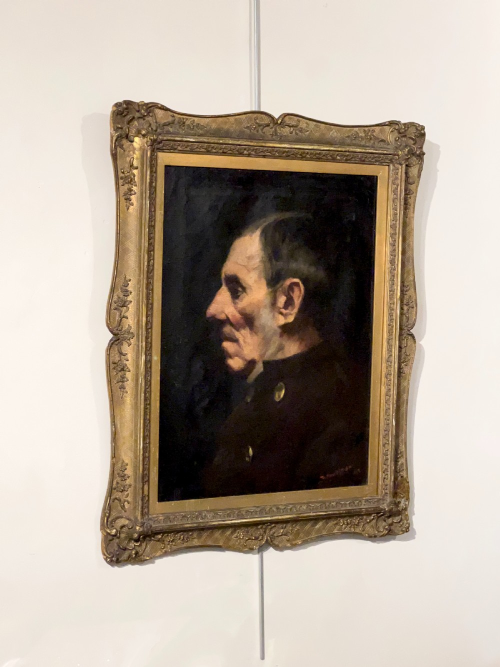 A side-profile oil portrait painting of a gentleman set within an ornate carved gilded wooden frame. View IV
