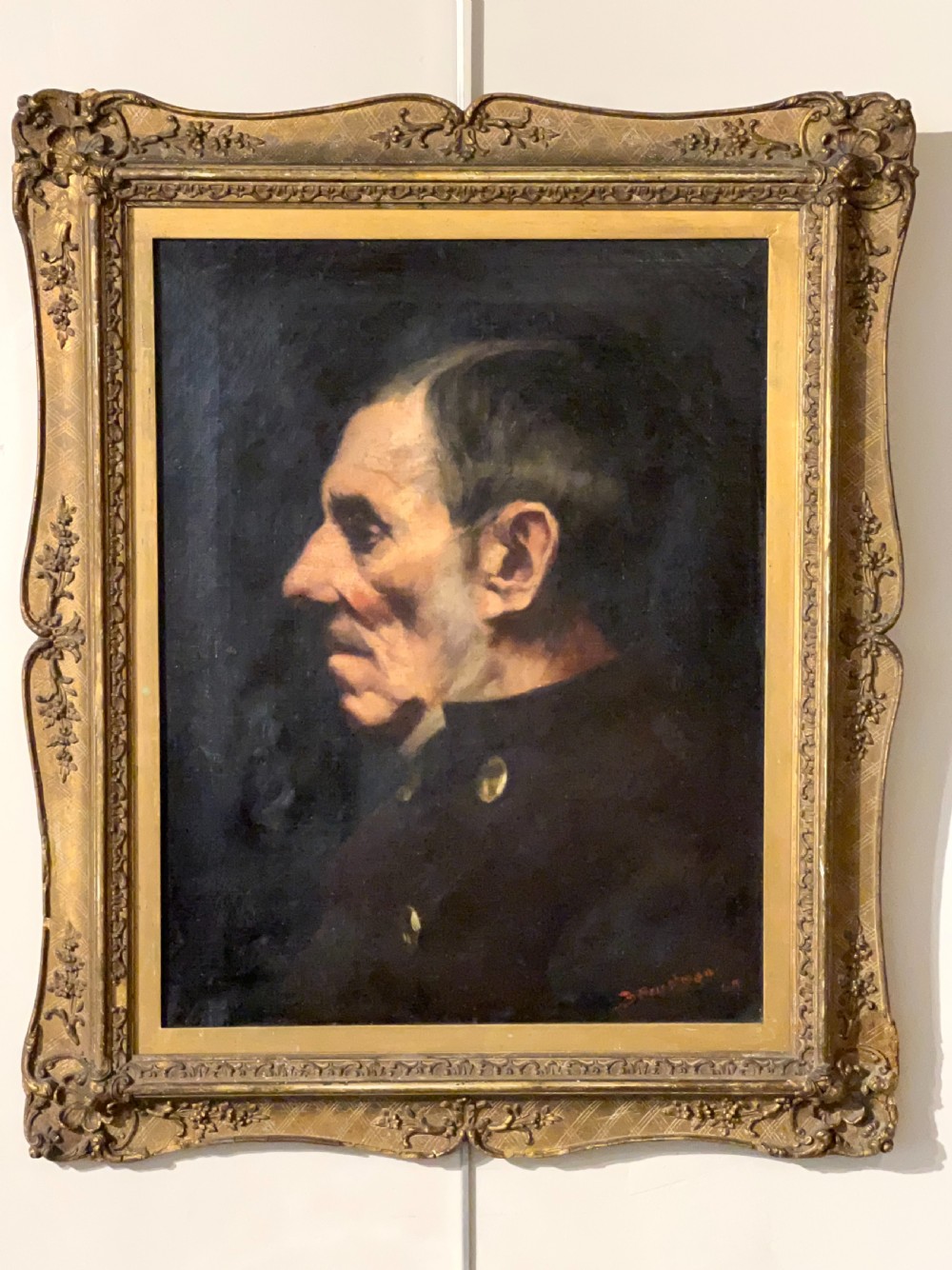 A side-profile oil portrait painting of a gentleman set within an ornate carved gilded wooden frame. View V