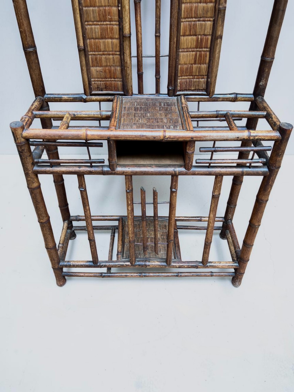 A dark Victorian bamboo hall stand featuring a central mirror, decorative ceramic lion tiles, coat hooks, and integrated umbrella racks. View VI