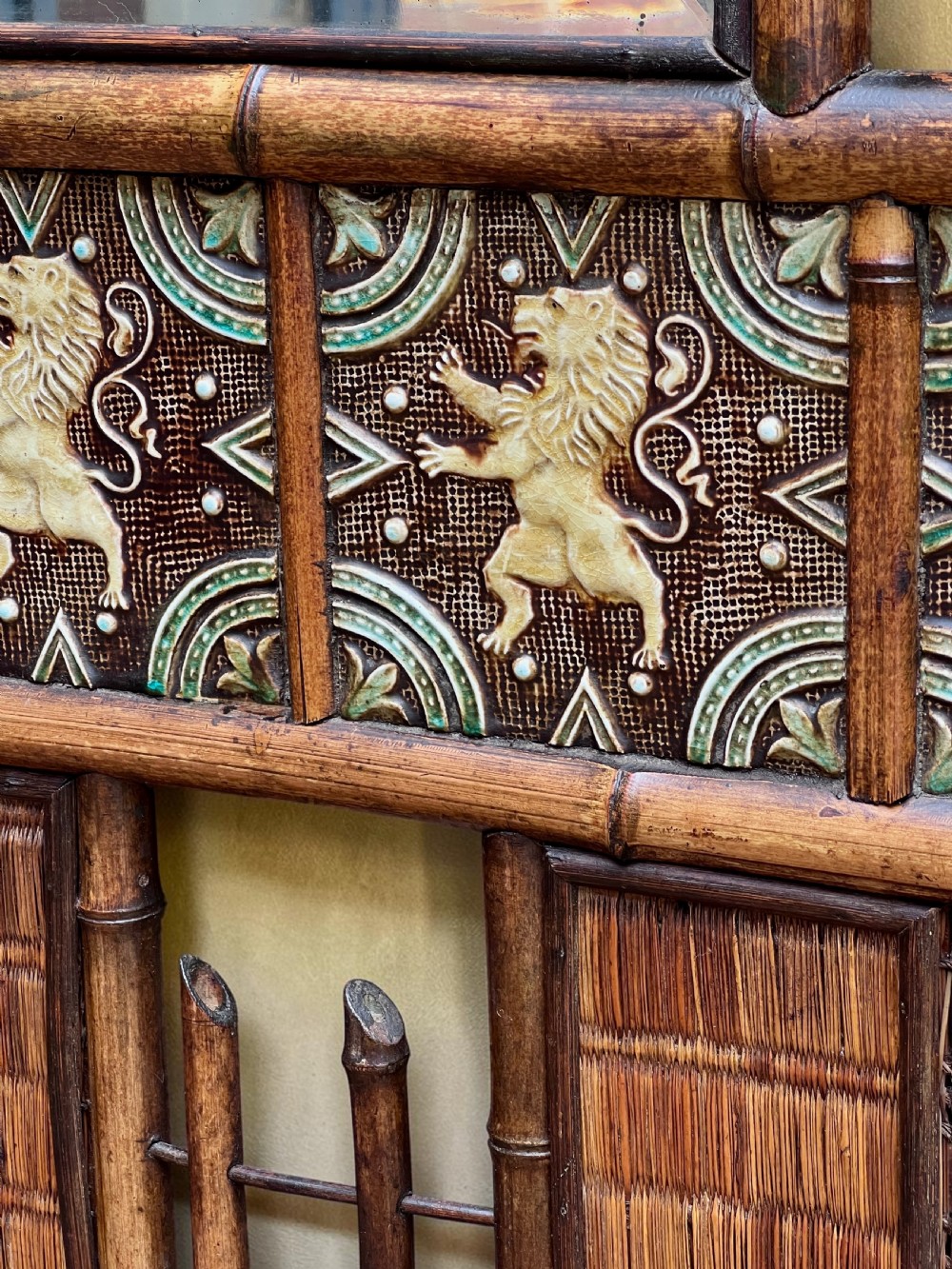 A dark Victorian bamboo hall stand featuring a central mirror, decorative ceramic lion tiles, coat hooks, and integrated umbrella racks. View VIII