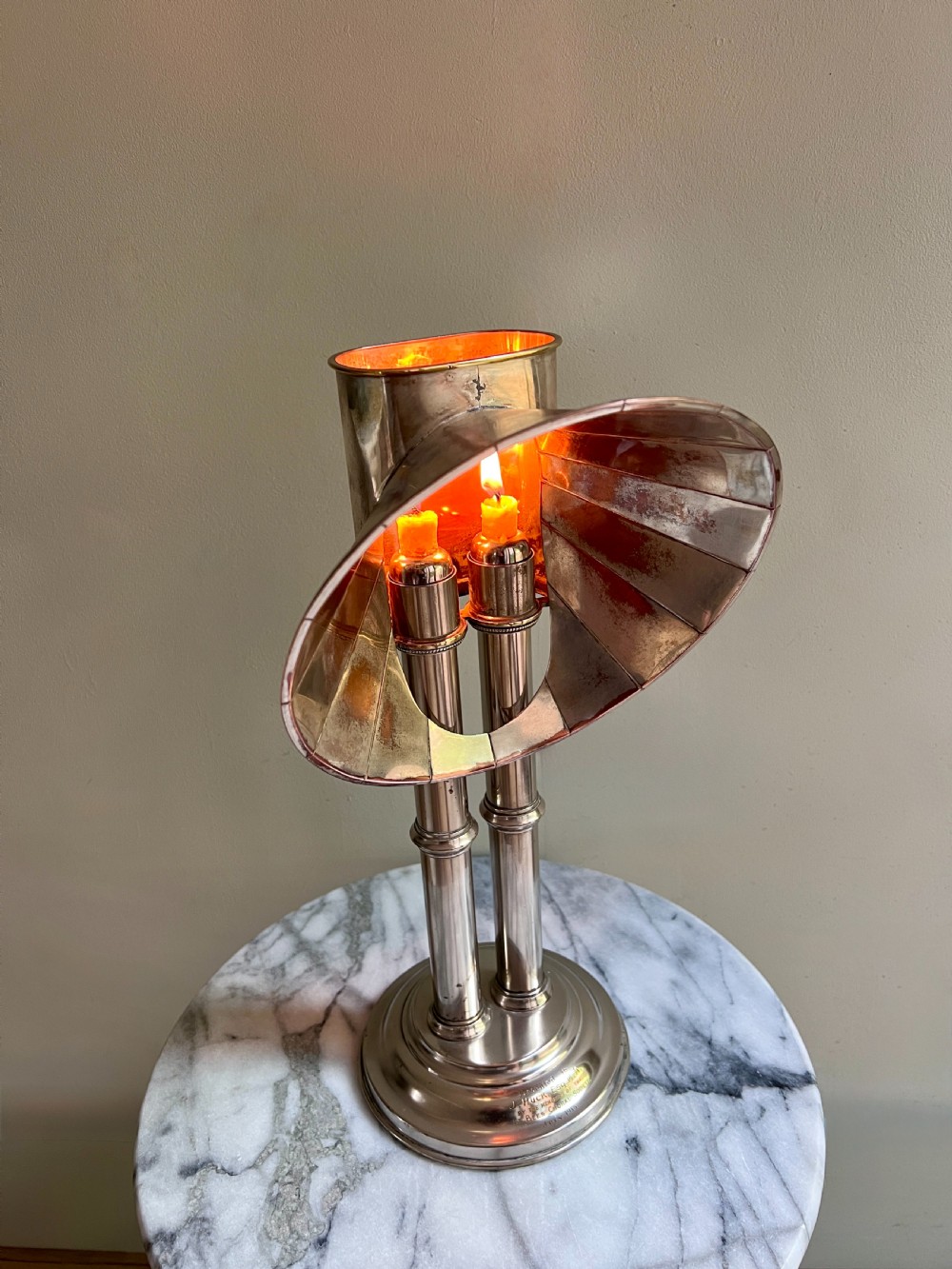 An Edwardian silver-plated candle lamp featuring twin column stems, a curved segmented reflector hood, and an engraved circular base. View X