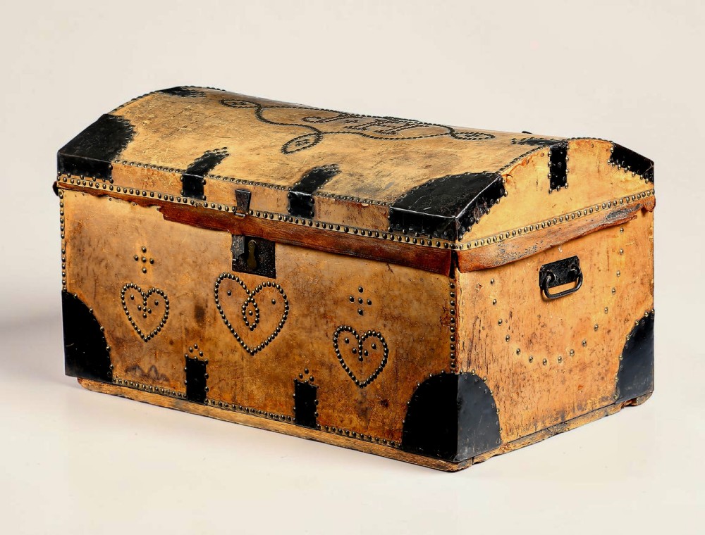 Victorian domed top tan leather trunk decorated with brass studwork, heart motifs, initials J H, and black metal corner brackets. View II