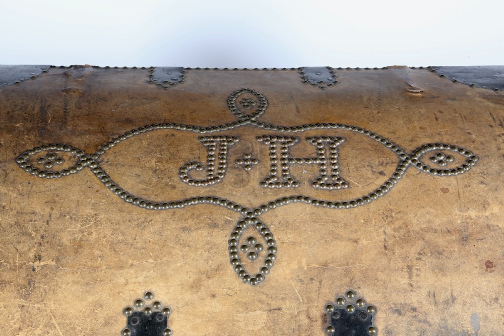 Victorian domed top tan leather trunk decorated with brass studwork, heart motifs, initials J H, and black metal corner brackets. View III