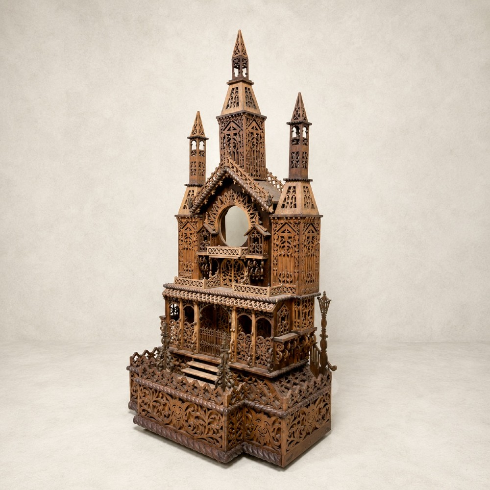 A carved wooden clock case designed in a Gothic cathedral architectural style with detailed fretwork, three spires, and a circular central opening. View V