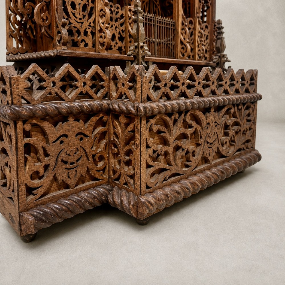 A carved wooden clock case designed in a Gothic cathedral architectural style with detailed fretwork, three spires, and a circular central opening. View VI