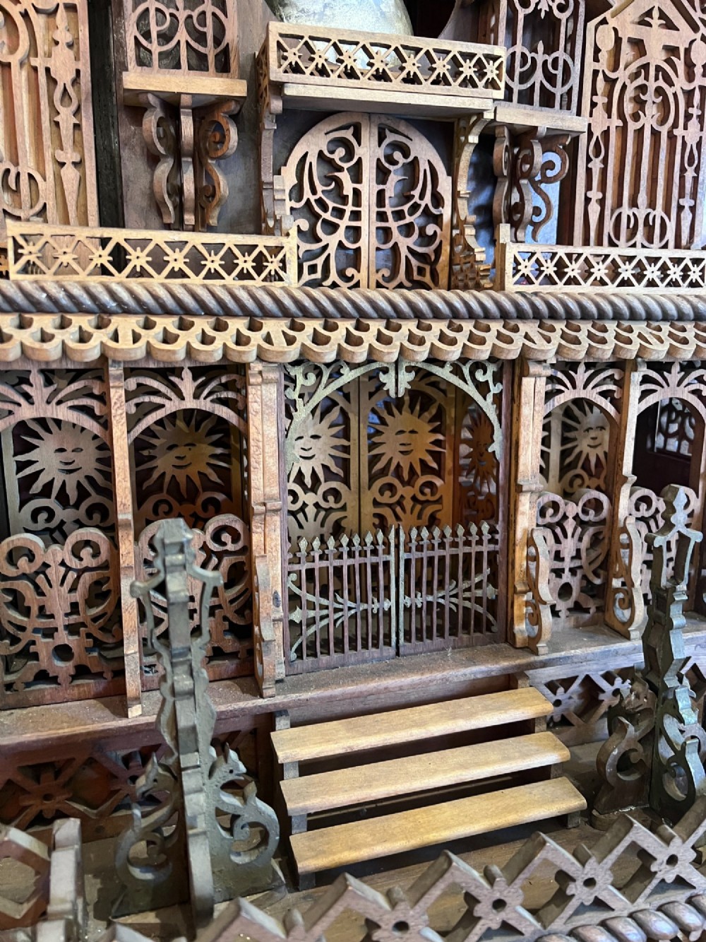 A carved wooden clock case designed in a Gothic cathedral architectural style with detailed fretwork, three spires, and a circular central opening. View X