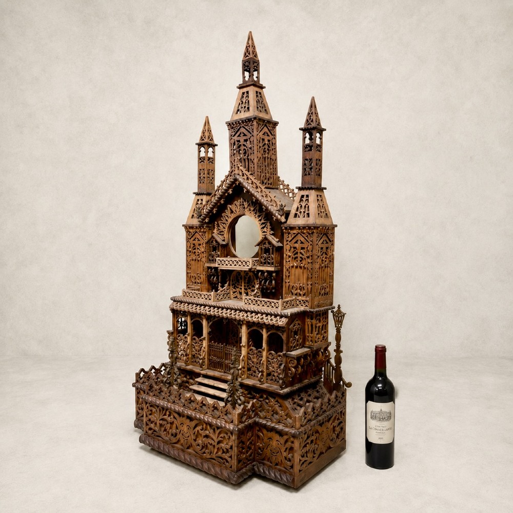 A carved wooden clock case designed in a Gothic cathedral architectural style with detailed fretwork, three spires, and a circular central opening. View XI