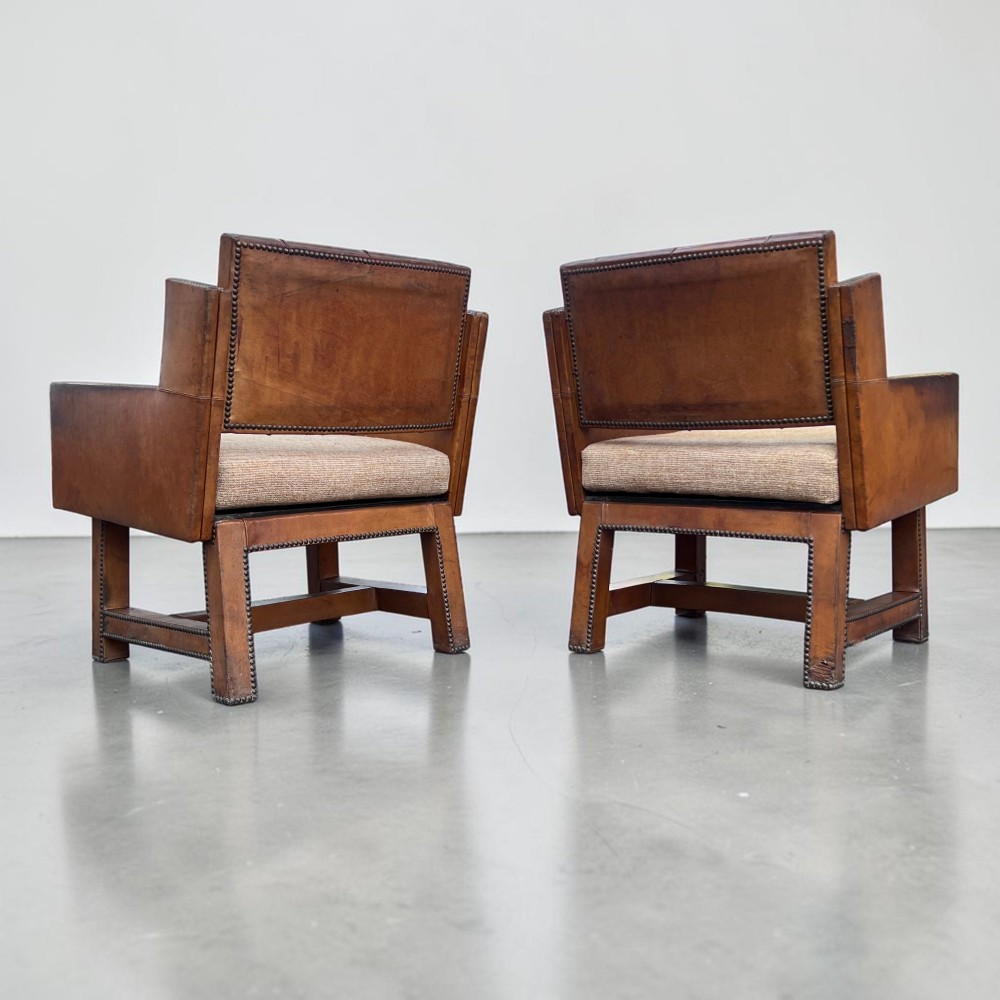 A pair of French 1930s cognac leather button-back armchairs with brass stud detailing and fabric seat cushions on wooden frames. View III