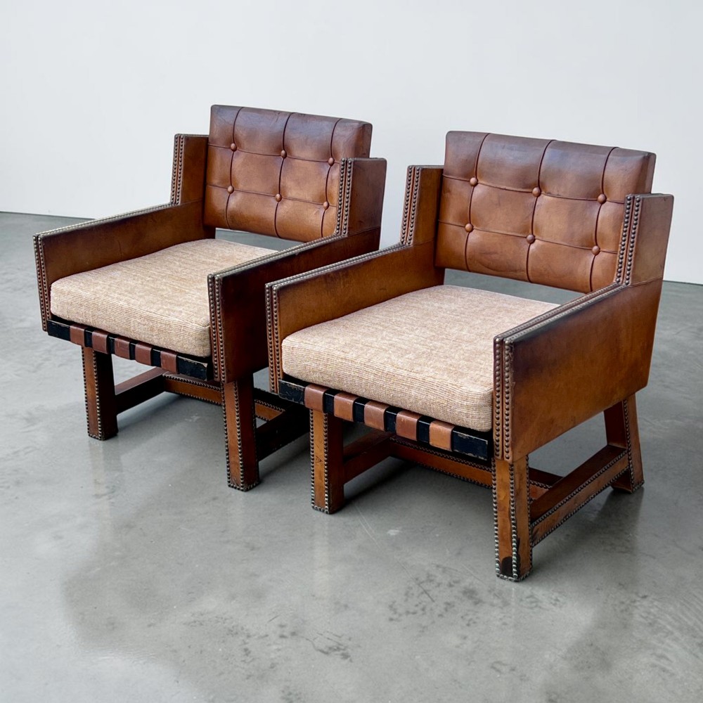 A pair of French 1930s cognac leather button-back armchairs with brass stud detailing and fabric seat cushions on wooden frames. View VI