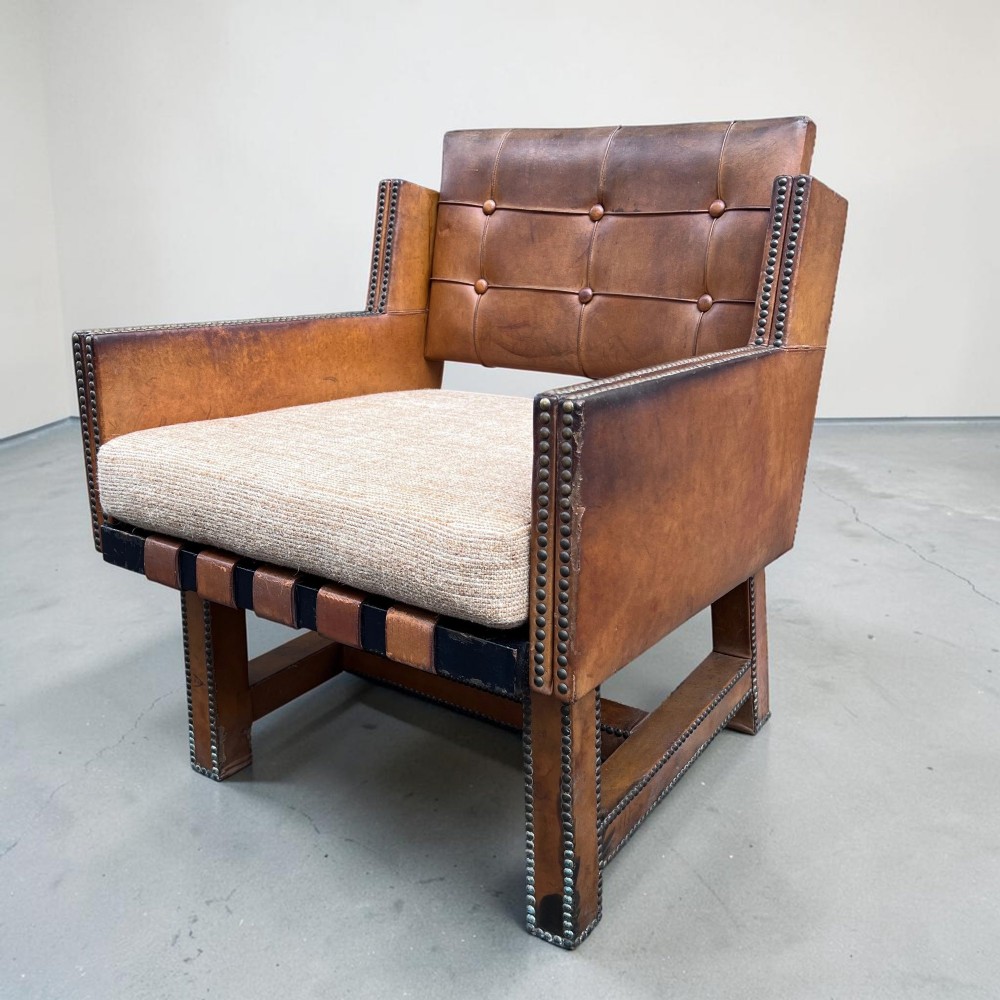A pair of French 1930s cognac leather button-back armchairs with brass stud detailing and fabric seat cushions on wooden frames. View VII