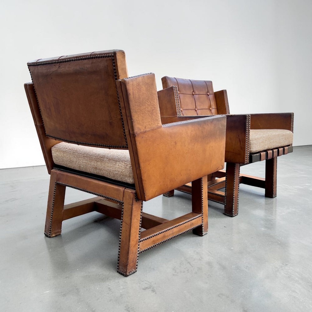 A pair of French 1930s cognac leather button-back armchairs with brass stud detailing and fabric seat cushions on wooden frames. View VIII