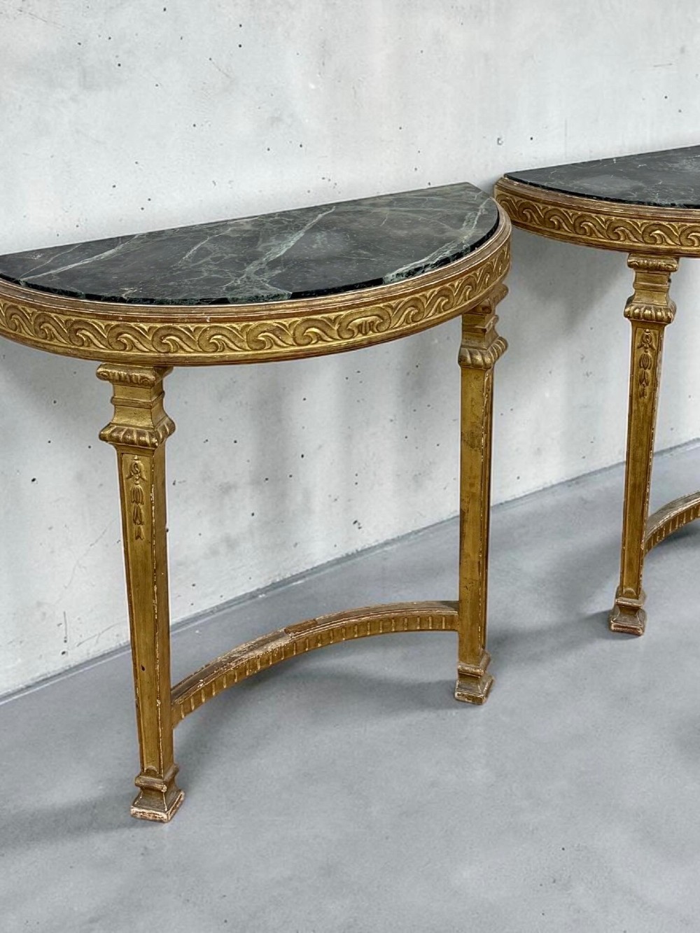 A pair of 19th-century Louis XVI Revival demilune console tables with carved gold giltwood frames and dark green marble tops. View II