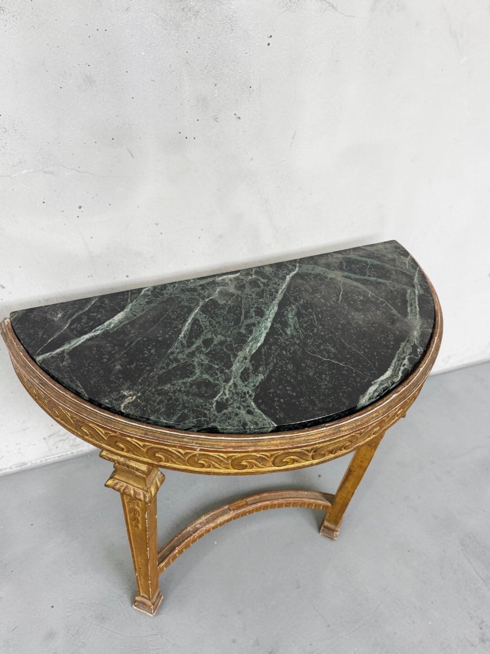 A pair of 19th-century Louis XVI Revival demilune console tables with carved gold giltwood frames and dark green marble tops. View III