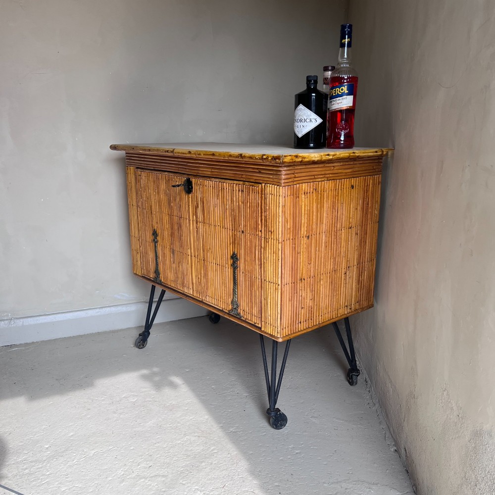A French 1930s drinks cabinet featuring reeded bamboo panelling, decorative iron strap hinges, and black cast-iron legs with small wheel castors. View VIII