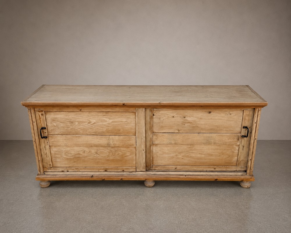 A large natural pine sideboard featuring two wide panelled doors with black metal handles and turned bun feet. View VI