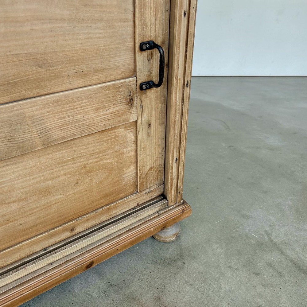 A large natural pine sideboard featuring two wide panelled doors with black metal handles and turned bun feet. View VIII