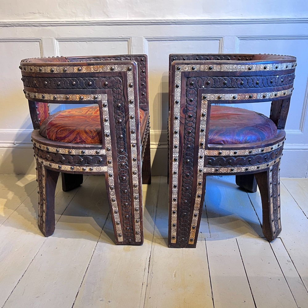 A pair of low curved hardwood armchairs featuring geometric bone inlay, brass stud detailing, and patterned red leather seats. View IV