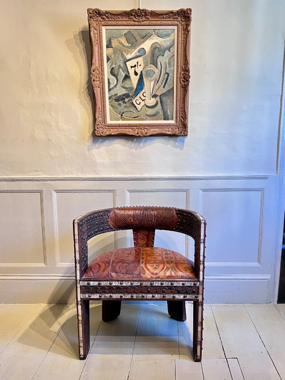 A pair of low curved hardwood armchairs featuring geometric bone inlay, brass stud detailing, and patterned red leather seats. View X