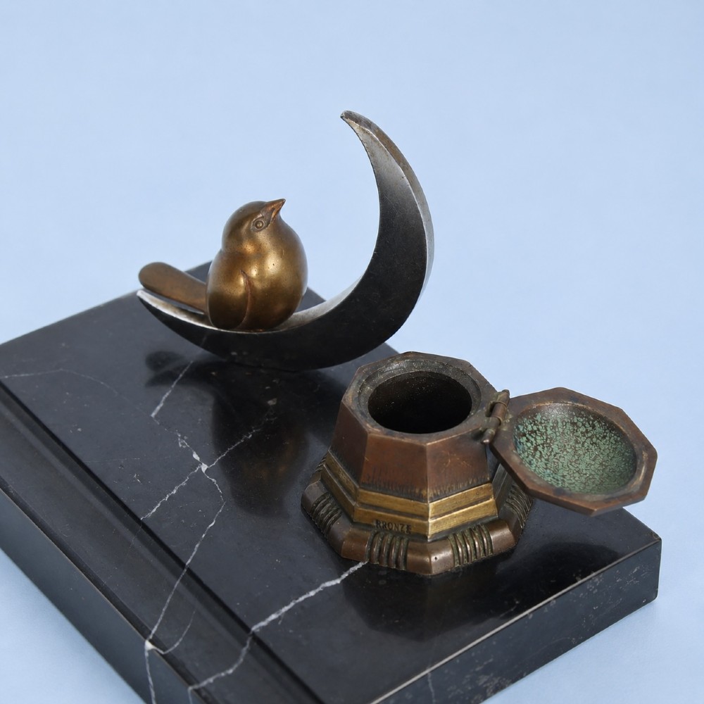 An Art Deco black marble desk tidy featuring a bronze bird perched on a silver-coloured crescent moon beside an octagonal metal inkwell. View III