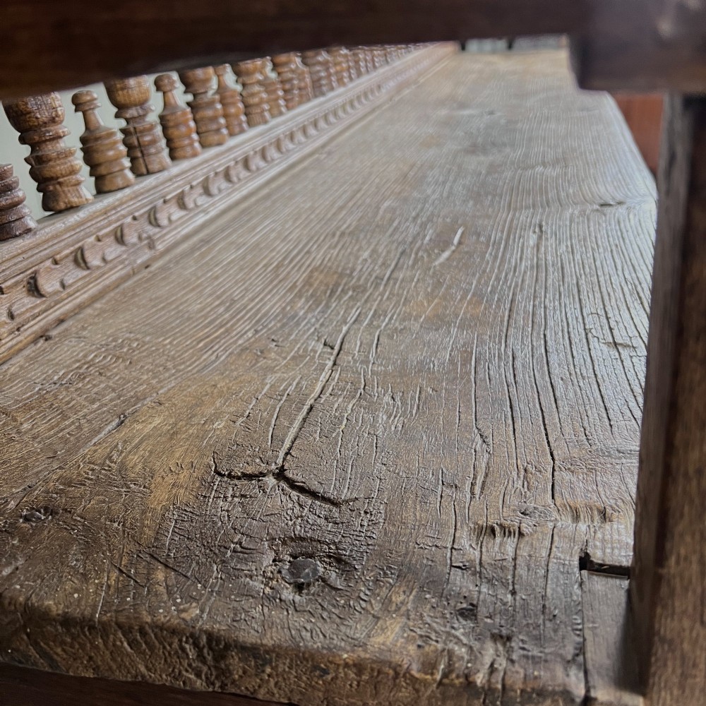 A large antique Spanish Colonial carved hardwood bench with floral relief carving and turned spindle details along the back and base. View VIII