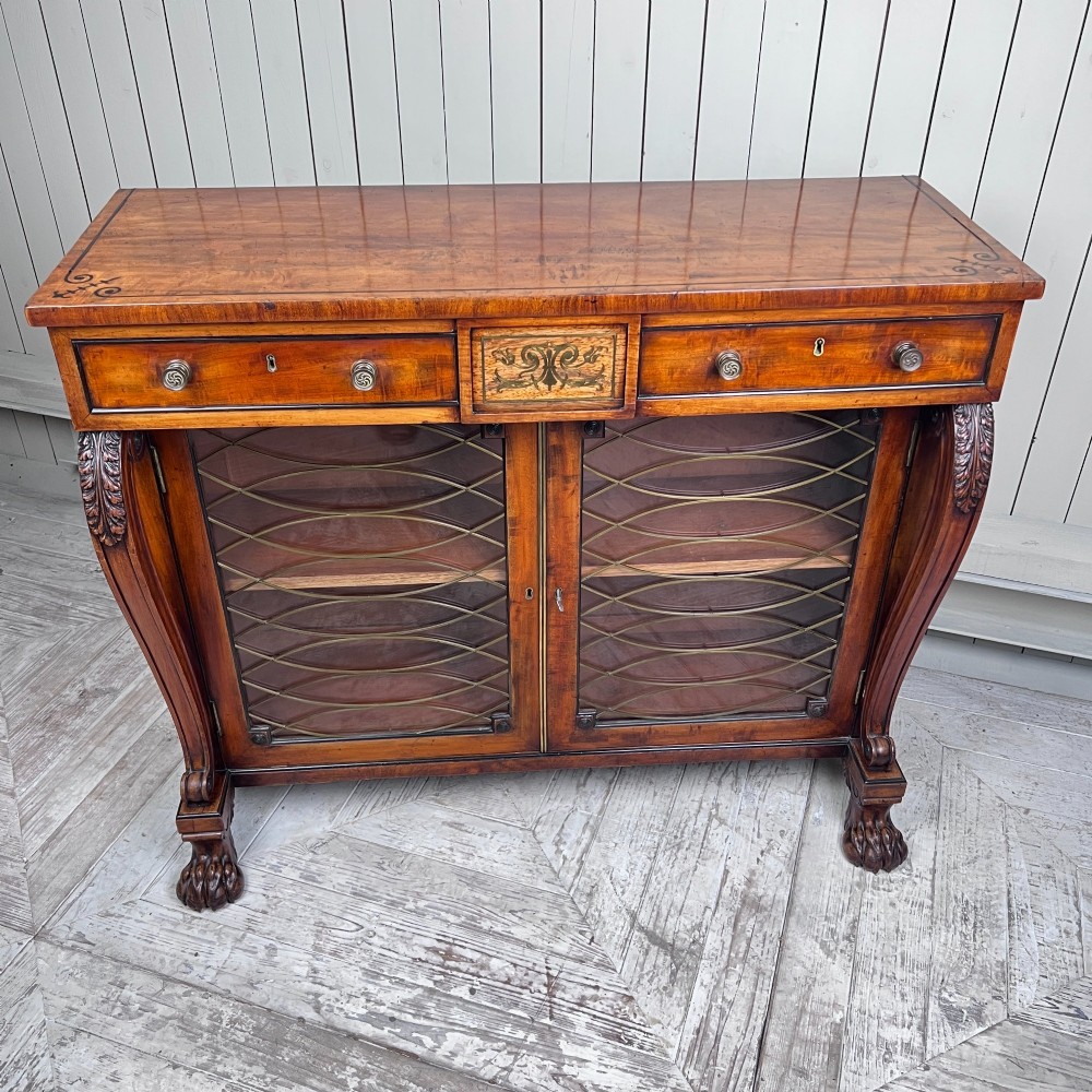 A Regency mahogany low chiffonier bookcase featuring brass wire grille doors, carved scroll supports terminating in paw feet, and brass inlay. View III